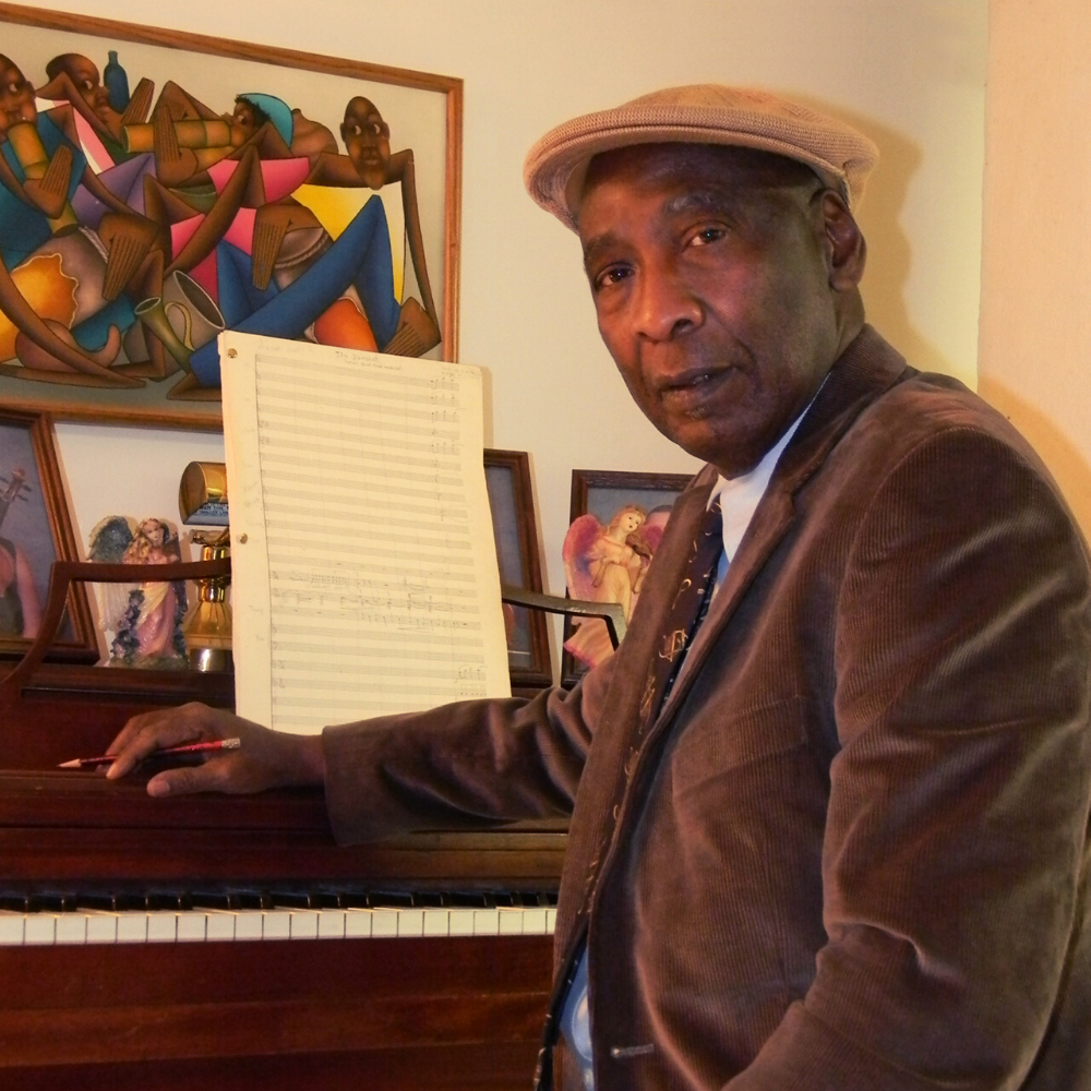 Man sitting at piano with hat on